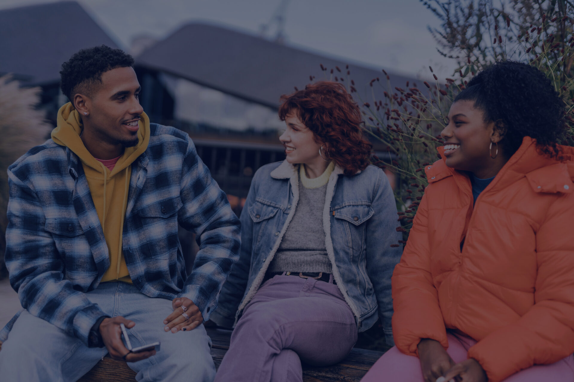 Three people sitting outdoors together and chatting.